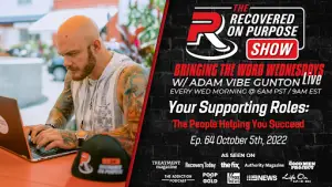 Bald man with tattoos works on a laptop beside a microphone; text promotes "Recovered On Purpose Show" about personal success airing October 5, 2022.