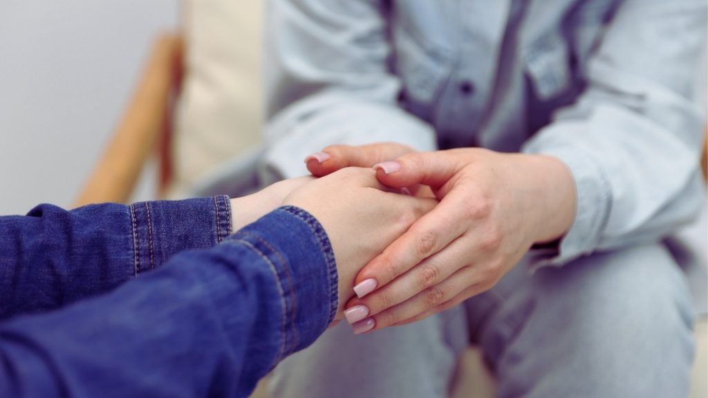 Close-up of two people holding hands during a vulnerable amends conversation.